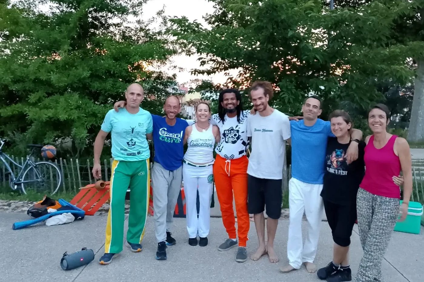 Huit adultes du groupe posés bras dessus bras dessous devant des arbres, après un entraînement en plein air